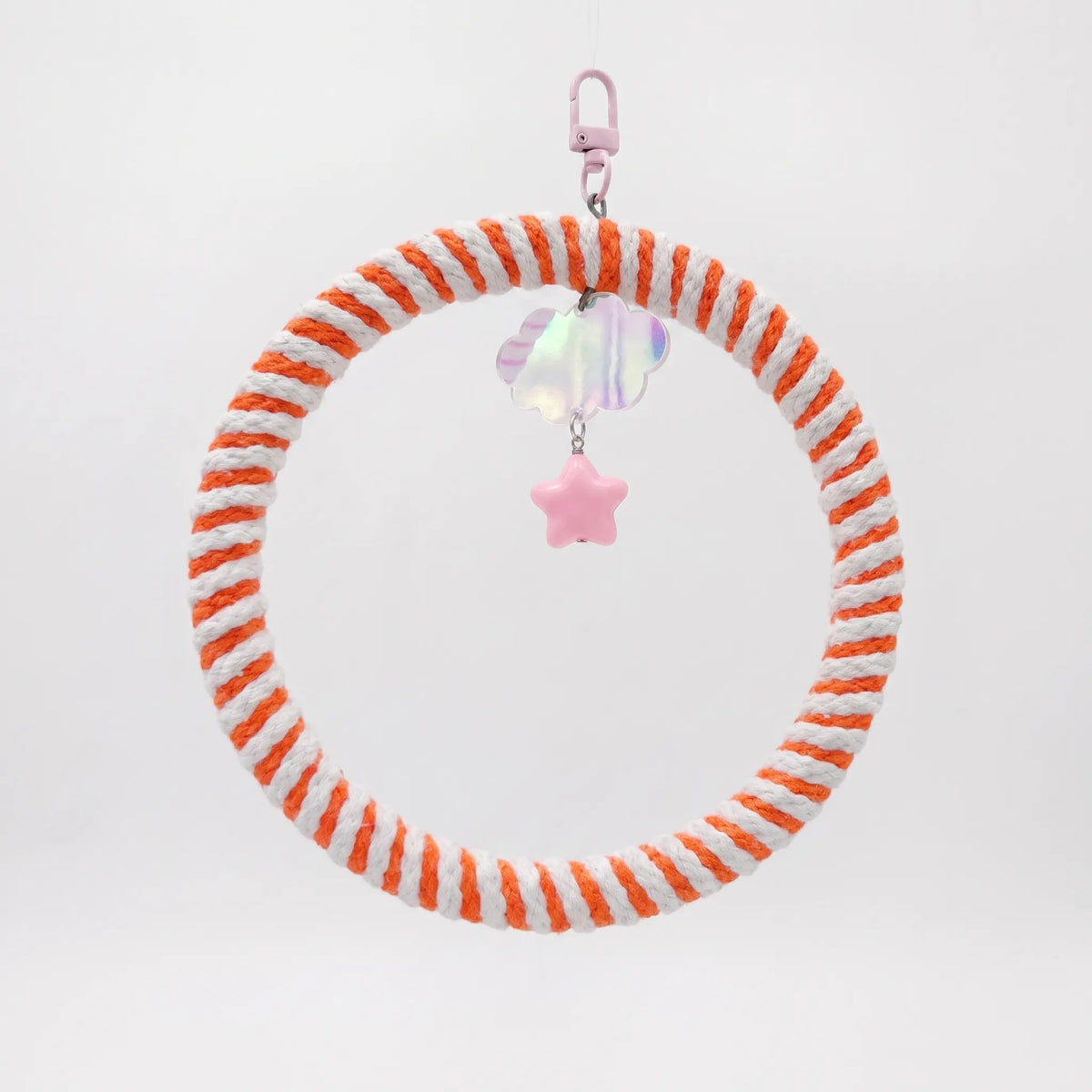 Hanging ring swing wrapped in orange and white cotton rope, with a pink clip, iridescent cloud charm and pink star bead. 1