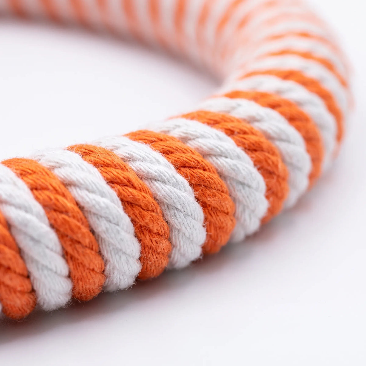 Close-up of the twisted cotton rope wrapping in alternating orange and white stripes along the curve of the ring. 3