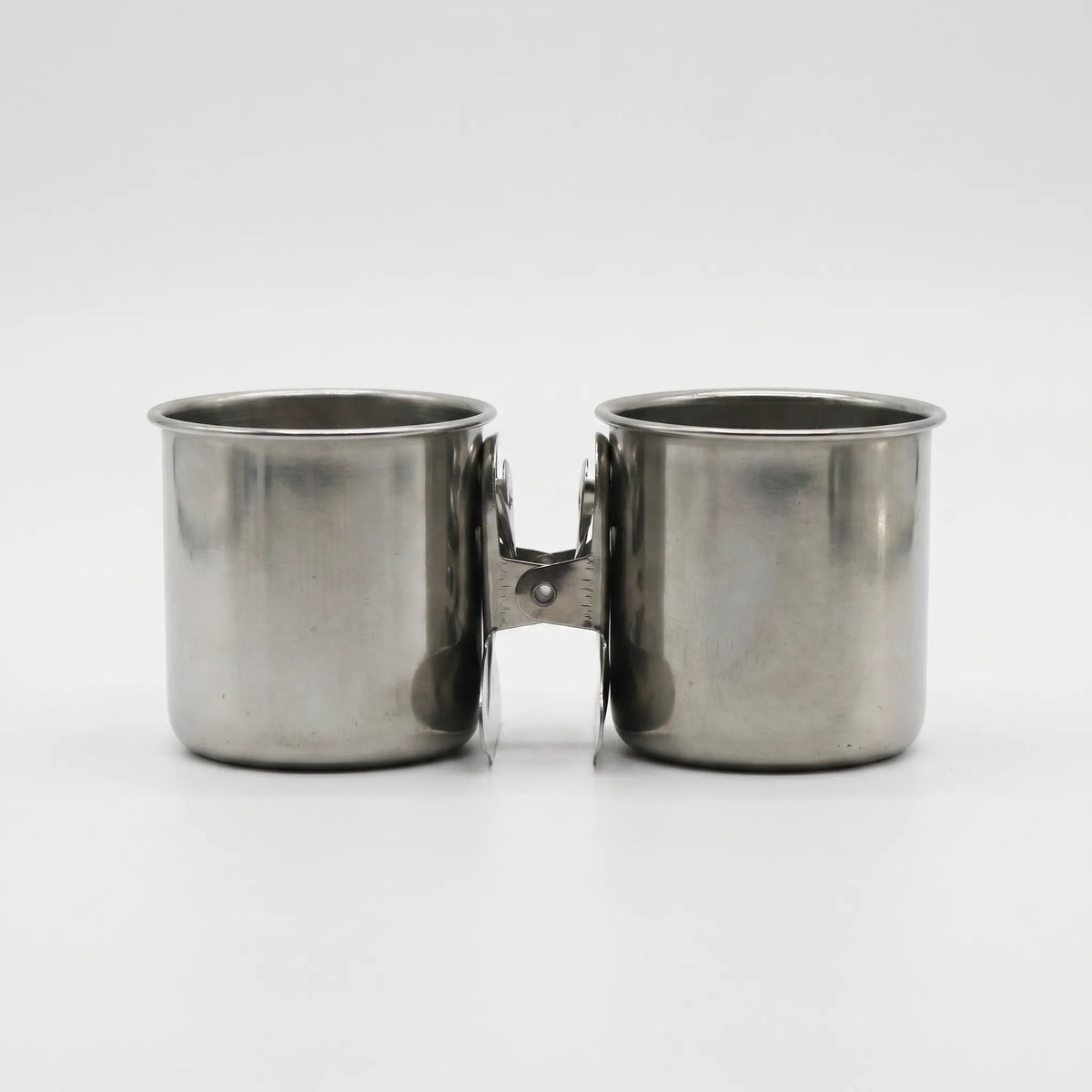Two steel cups joined back to back by one spring clip, seen from the front on white. 7