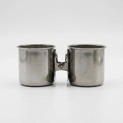 Two steel cups joined back to back by one spring clip, seen from the front on white. 7