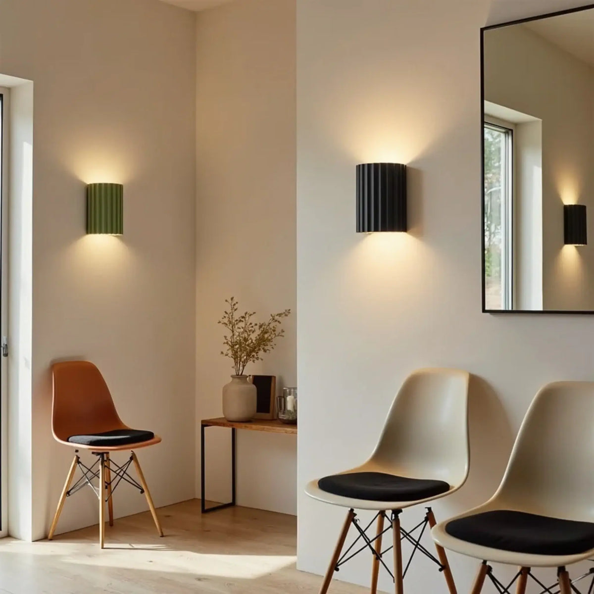 Green and black fluted wall lights glowing in a bright hallway with moulded chairs and a mirror 3