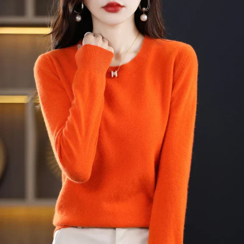 Bright orange round-neck jumper on a model with a hand raised near the collar, showing the ribbed cuff 5