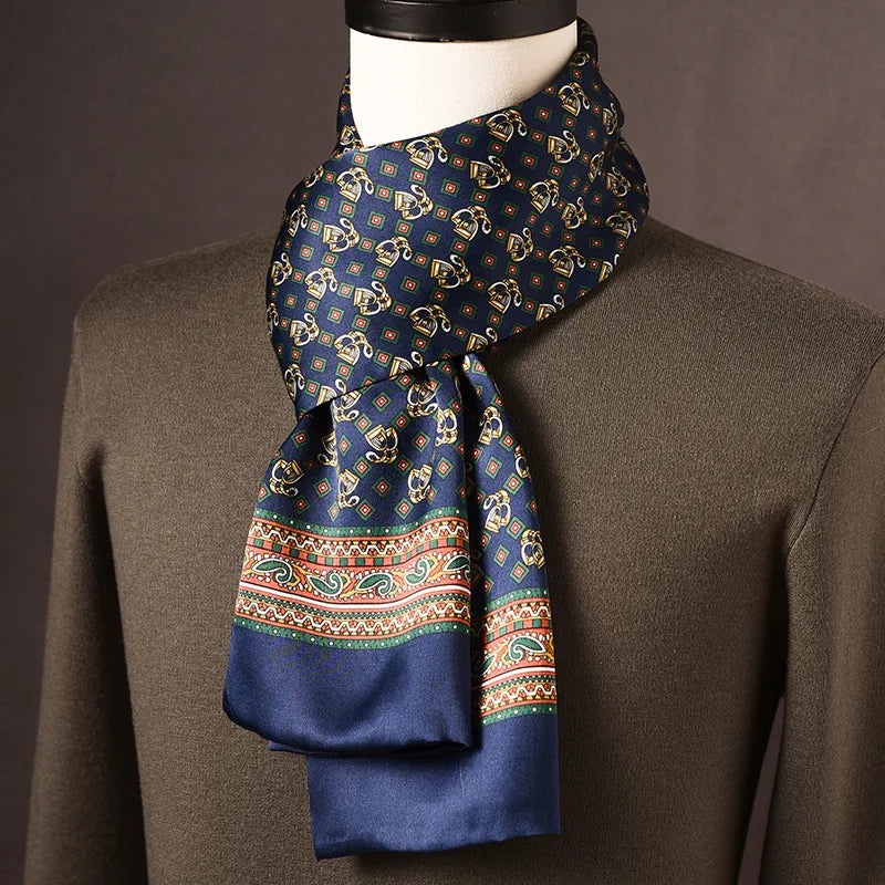 Navy silk scarf with gold stirrup-style motifs and a green, orange and white paisley border, on a mannequin in an olive jumper. 20