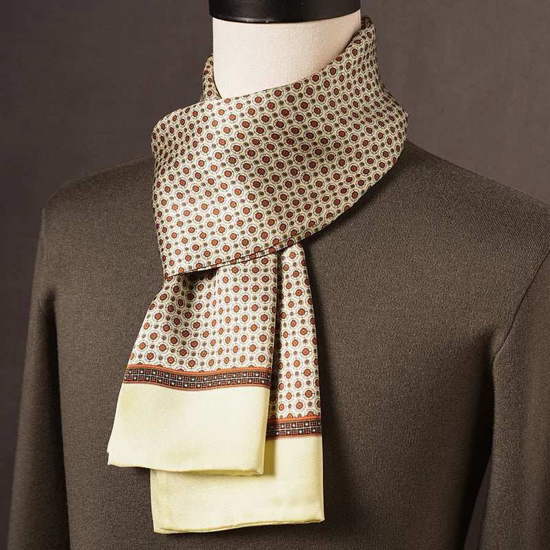 Cream silk scarf with small orange-red circular motifs, a brown patterned border and pale yellow ends, on a mannequin in an olive jumper. 9