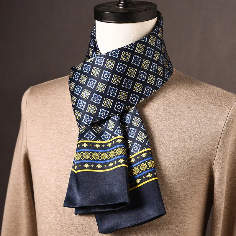 Navy silk scarf with blue and yellow square motifs and a yellow and blue striped border, draped on a mannequin in a beige jumper. 22
