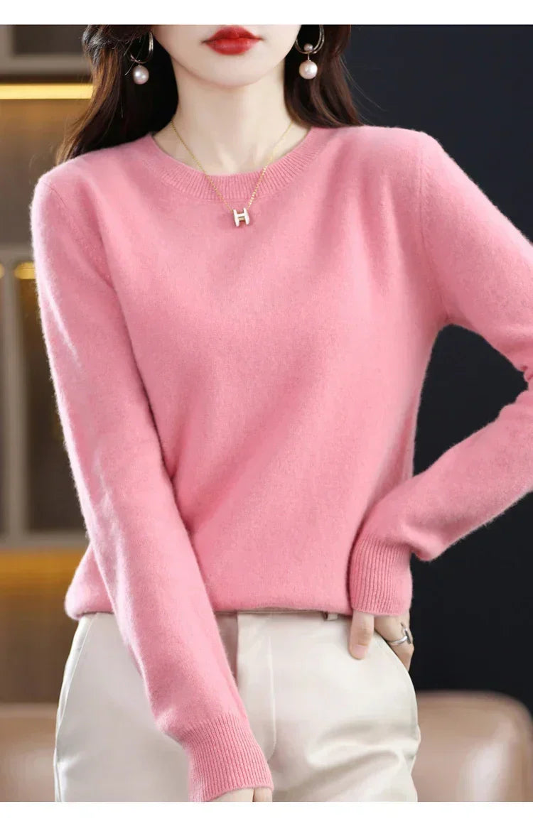 Pink crew-neck jumper with ribbed hem and cuffs, worn with cream trousers and a hand on hip 8