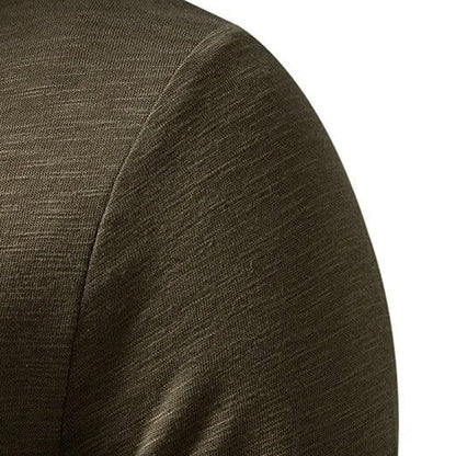 Close-up of the olive green Henley's shoulder and sleeve seam, showing the slub-textured cotton fabric. 8