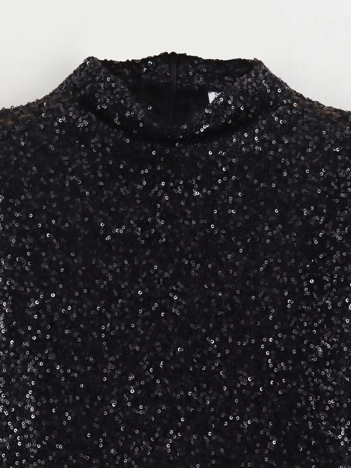Close-up of the black sequin fabric at the high neckline, with a back zip visible 4