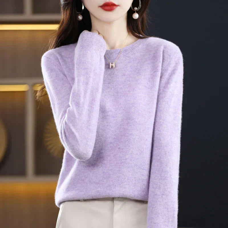 Pale lilac round-neck jumper with a soft texture, worn with cream trousers and hand raised to the shoulder 17