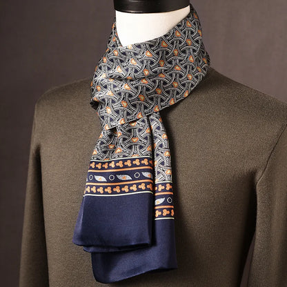 Navy silk scarf with an interlocking orange and white arc pattern and a decorative border, draped on a mannequin in an olive jumper. 11