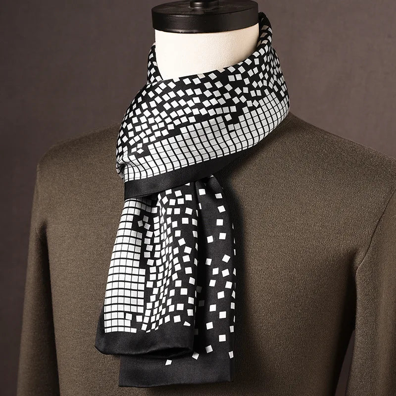 Black and white silk scarf with a scattered square mosaic pattern and black edging, on a mannequin in an olive jumper. 13