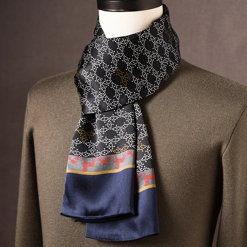 Black silk scarf with white dotted curves, red stag motifs on a grey band and navy ends, on a mannequin in an olive jumper. 16