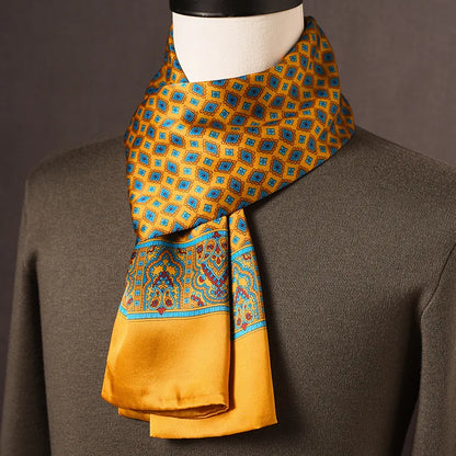 Golden-yellow silk scarf with blue diamond motifs and an ornate paisley border, draped on a mannequin in an olive jumper. 5