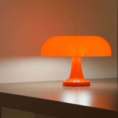 Orange lamp lit on a shelf edge against a warm orange-washed wall, showing the shade and flared stem in profile. 6