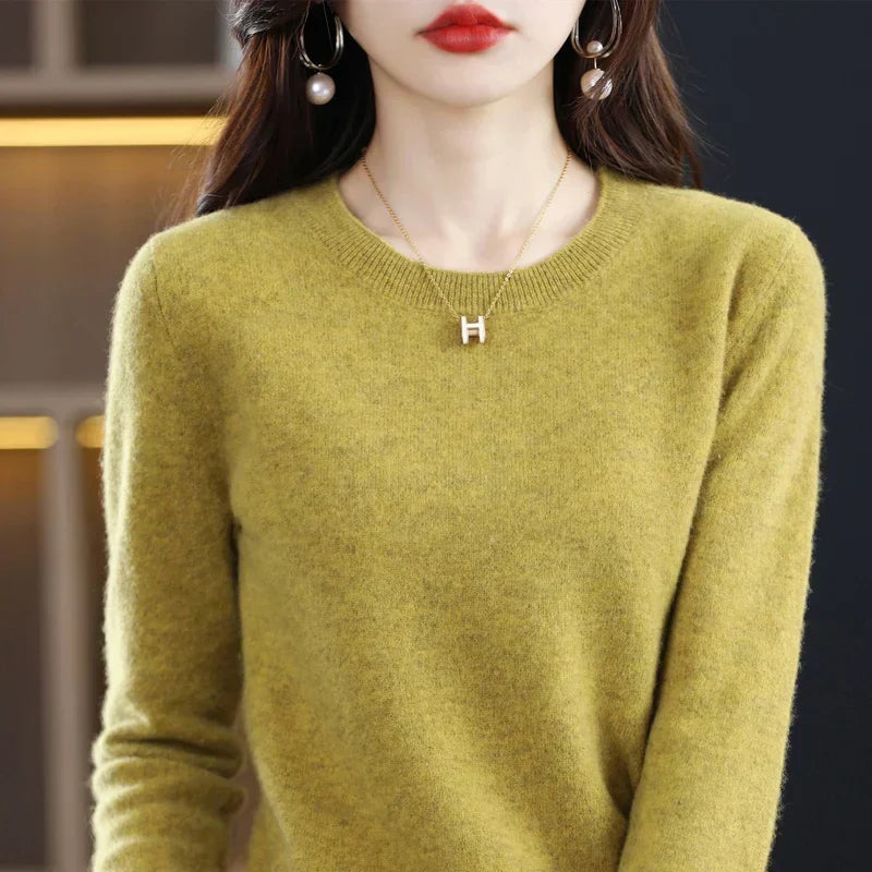 Close-up of a mustard-yellow round-neck jumper with ribbed collar, worn with pearl earrings and a pendant necklace 1