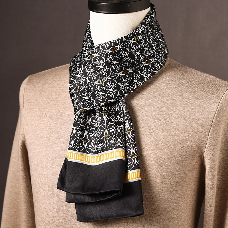 Black silk scarf with a white scrollwork pattern and a yellow chain-link border, draped on a mannequin in a beige jumper. 25