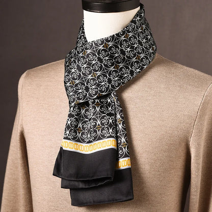Black silk scarf with a white scrollwork pattern and a yellow chain-link border, draped on a mannequin in a beige jumper. 25