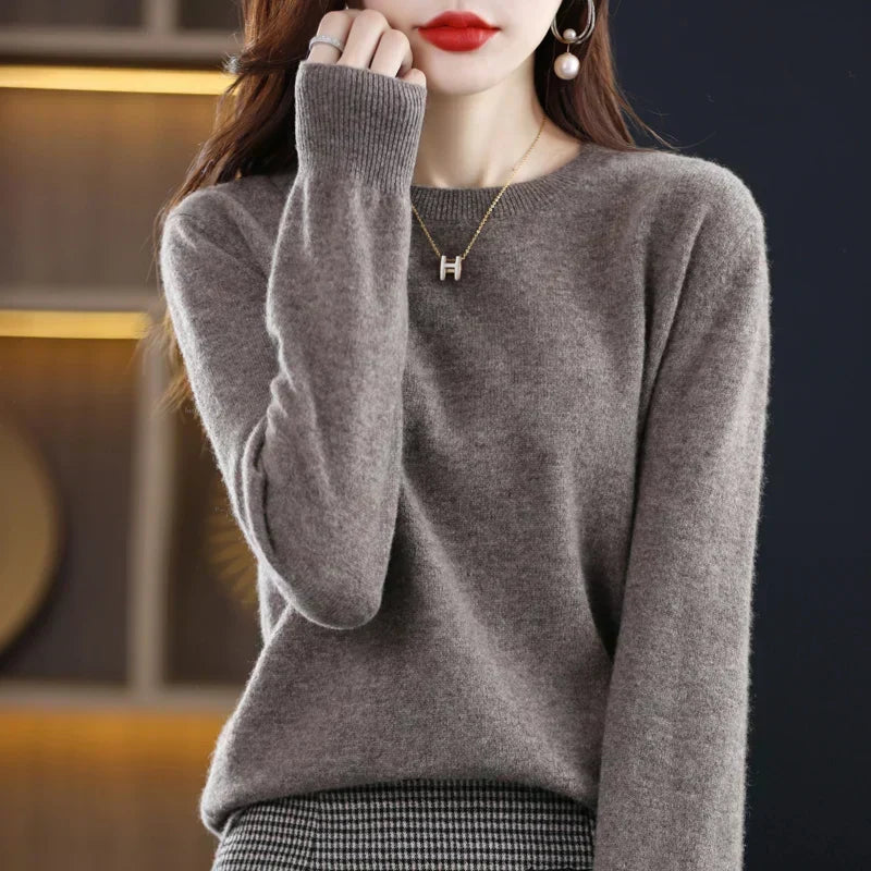 Grey-brown crew-neck jumper worn with a houndstooth skirt, one hand raised to the chin showing the ribbed cuff 4
