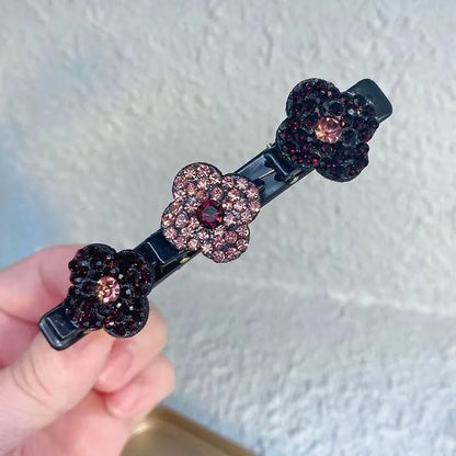 Hand holding one black clip with three flowers covered in dark burgundy and dusky pink rhinestones, each with a pink centre. 4
