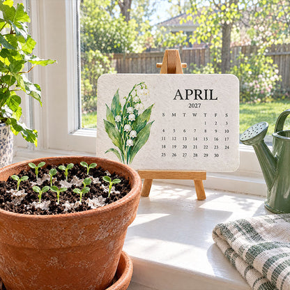 April card with lily of the valley on an easel by a window, beside a pot of sprouting seedlings 11