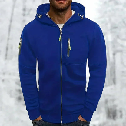 Model wearing the zip-up hoodie in royal blue with lime green zip pulls, hands in pockets against a snowy backdrop. 1