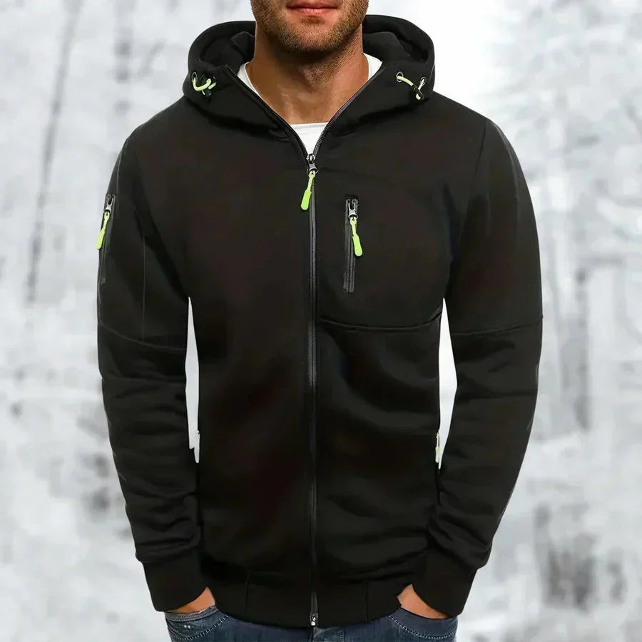 Model wearing the hoodie in black with lime green zip pulls, showing chest and sleeve zip pockets against a snowy backdrop. 7