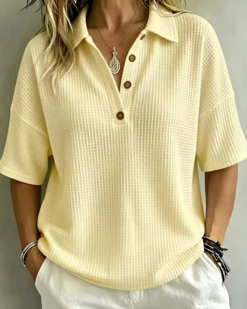 Front view of the pale yellow waffle knit polo top worn with white trousers and a pendant necklace 2