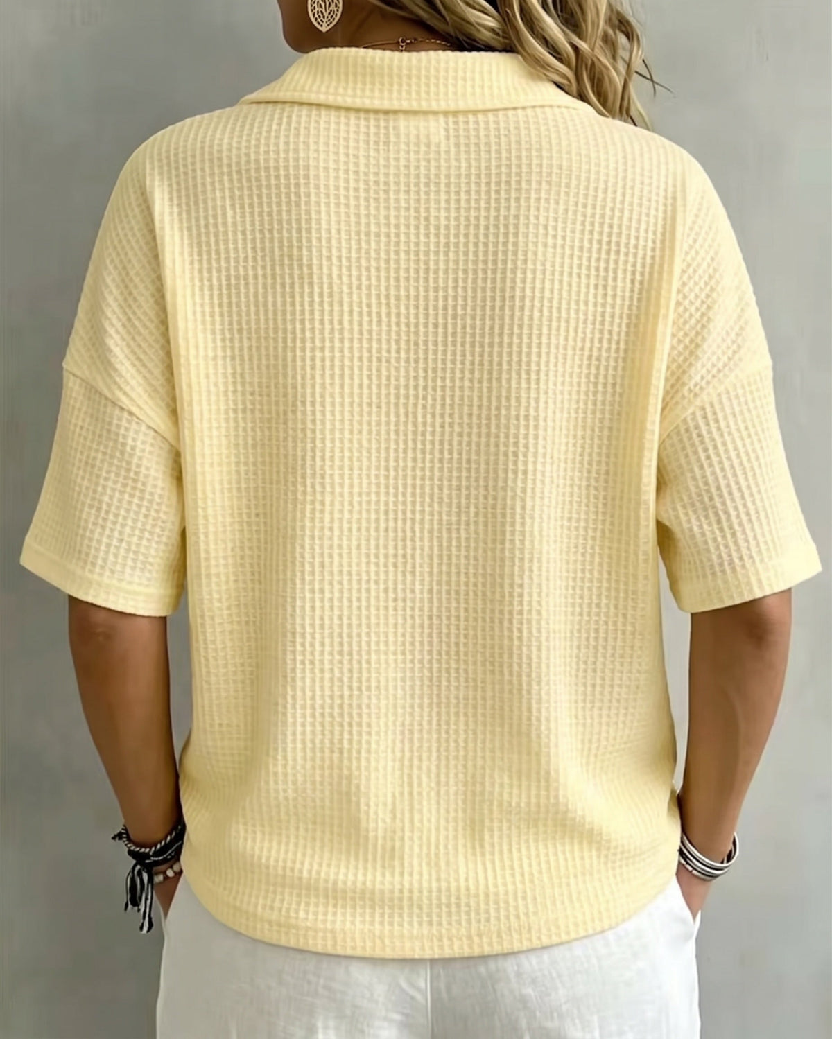 Back view of the pale yellow waffle knit polo top, showing the folded collar and drop shoulders 3
