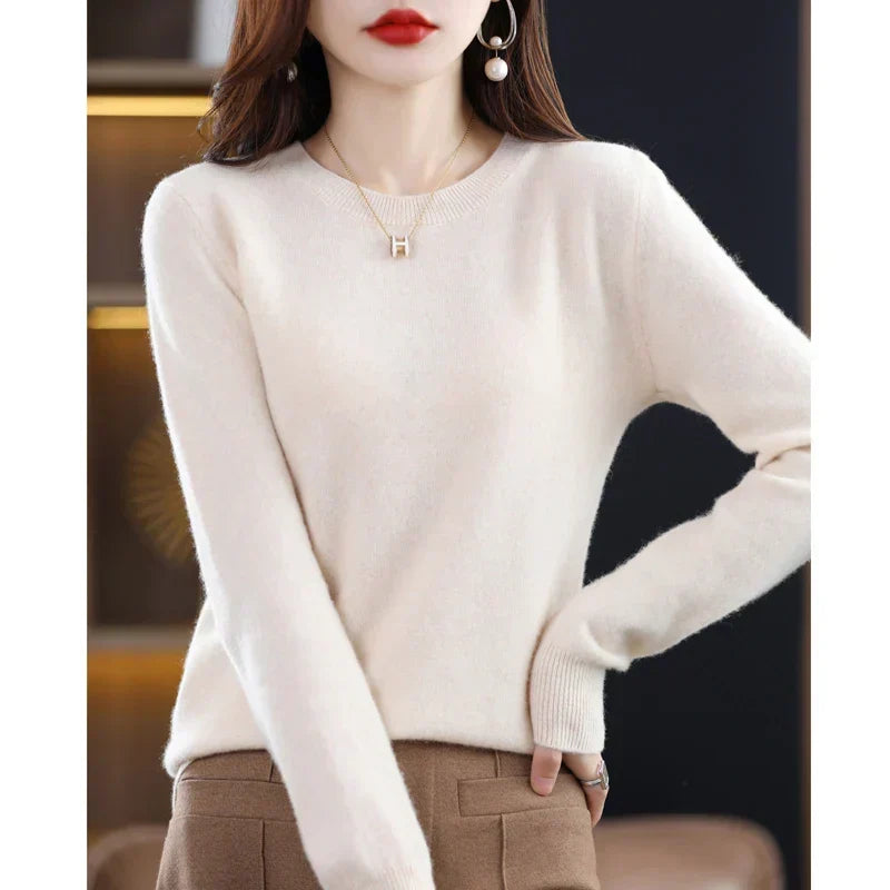 Cream crew-neck jumper worn with brown trousers, one hand on hip, showing the ribbed cuff 18