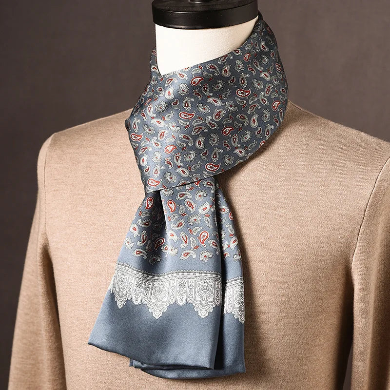 Grey-blue silk scarf with red and white paisley motifs and a white lace-like border, styled on a mannequin in a beige jumper. 18