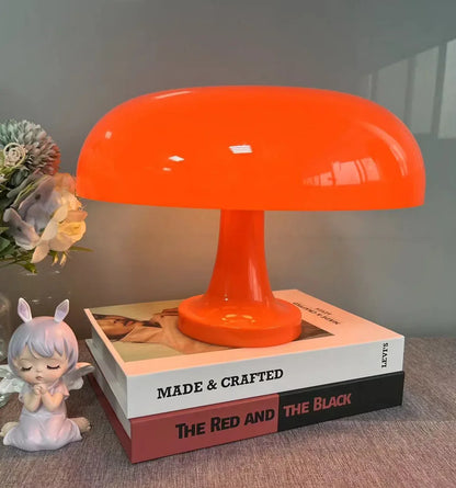 Orange lamp standing on two stacked books next to an angel figurine and a bunch of flowers. 7