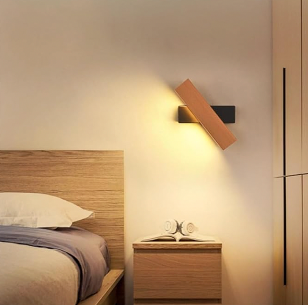 Wooden light with a black base tilted above a bedside table, next to a wooden bed headboard. 6