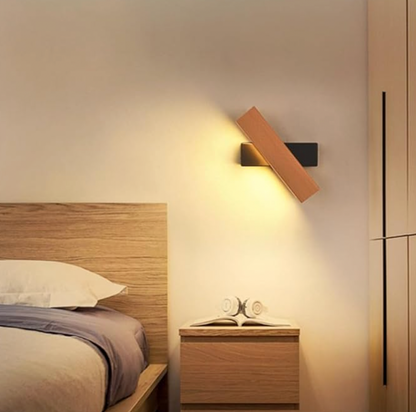 Wooden light with a black base tilted above a bedside table, next to a wooden bed headboard. 6