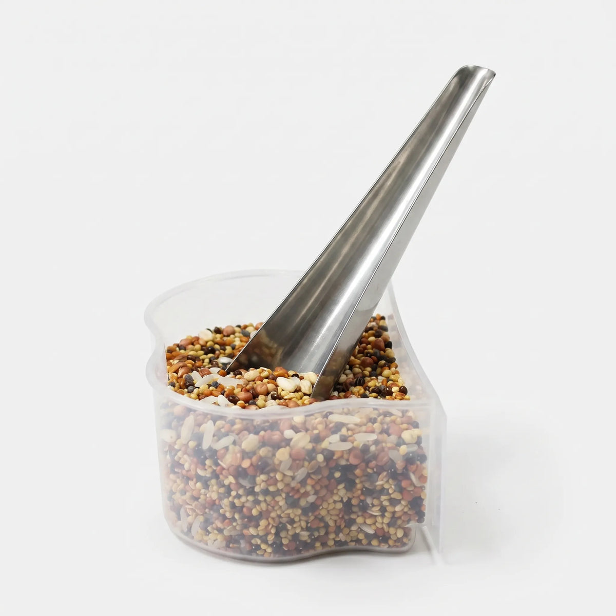 Metal scoop standing in a clear plastic container filled with mixed bird seed, shown against a plain white background. 1