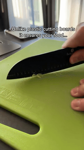 Black knife cutting food on a lime green plastic board, shown as a comparison with the metal board. 6