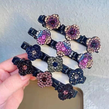 Four black hair clips, each with three rhinestone flowers in different colour schemes, held in a hand against a textured wall. 1