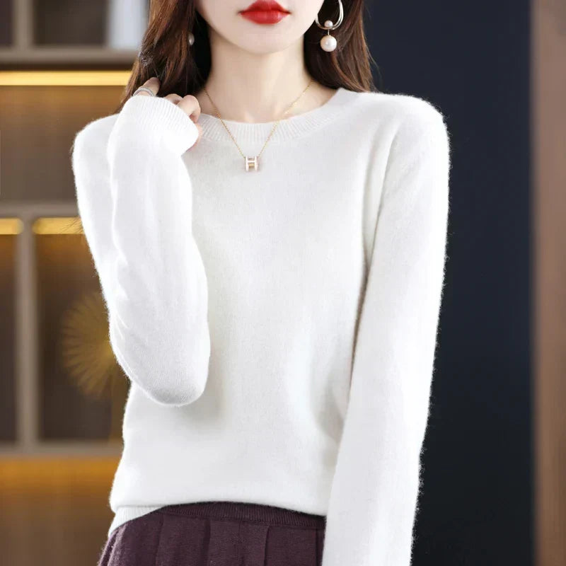 Cream-white round-neck jumper worn with a dark burgundy pleated skirt, hand raised to the shoulder 7