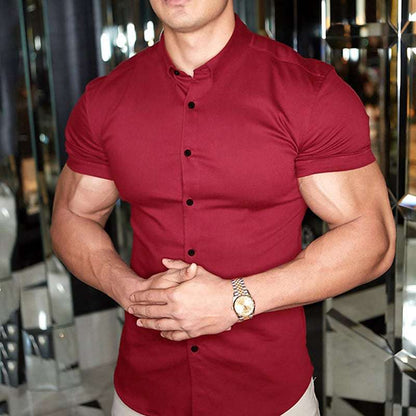 Burgundy red short sleeve shirt with black buttons, worn by a model with clasped hands and a gold-toned watch. 4
