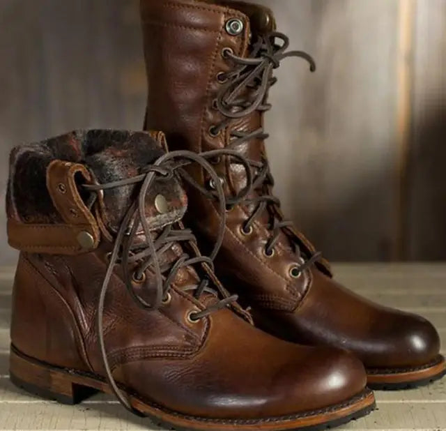 Brown leather lace-up boots, one with the cuff folded down to reveal a dark patterned lining, on a pale wooden surface. 3