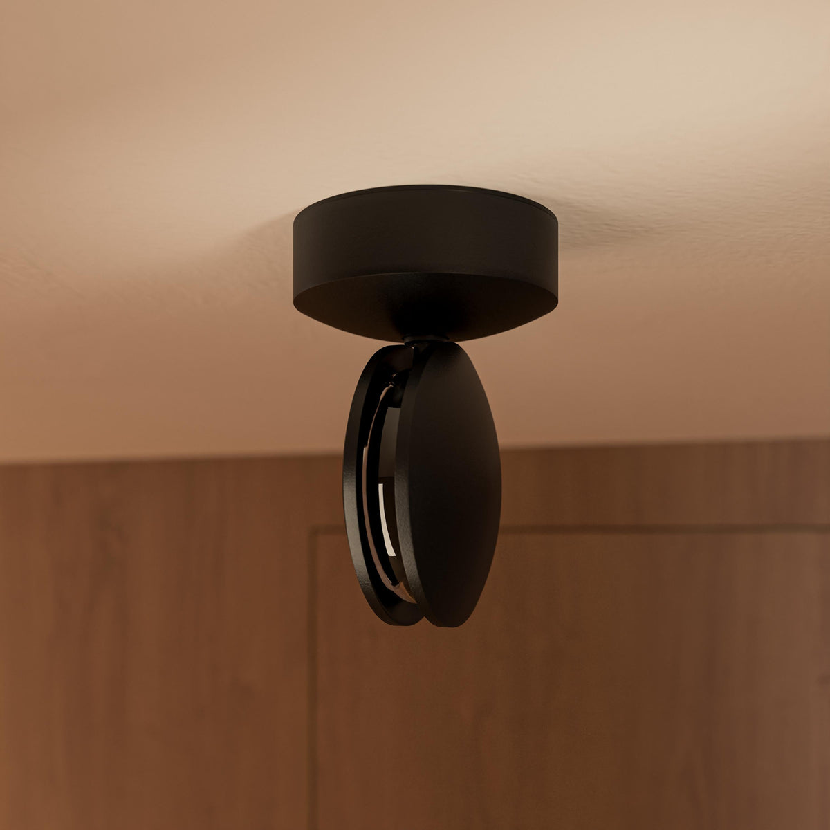Black ceiling light with its round head turned sideways, showing the slim gap where the light emerges, against a wooden wall. 13