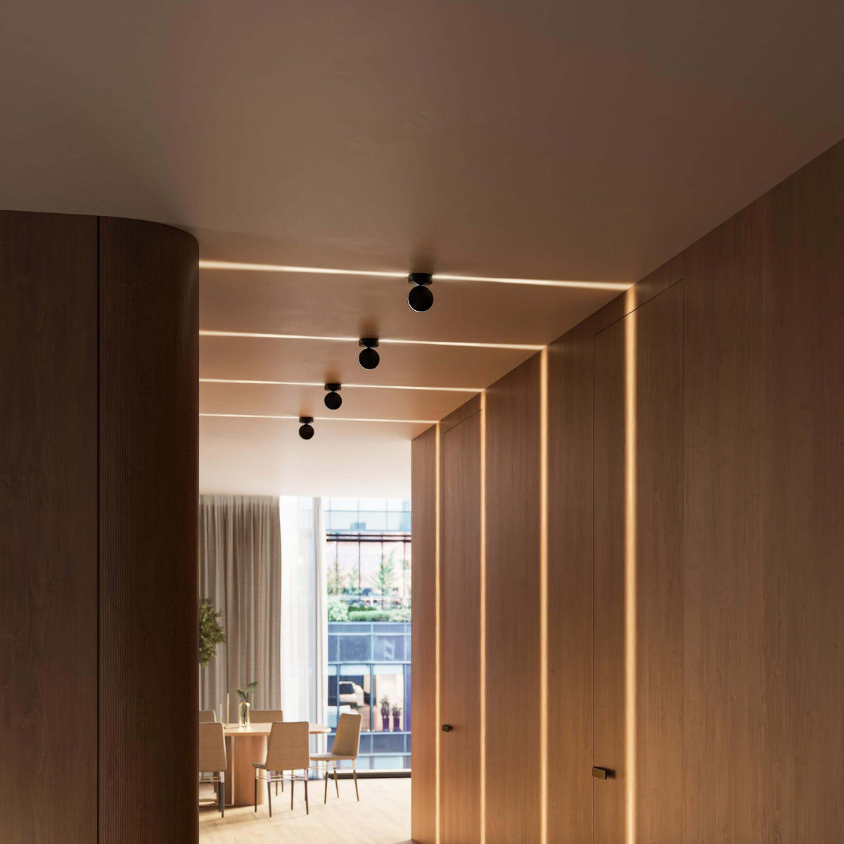 Black ceiling lights in a wooden corridor casting warm lines of light on ceiling and walls, with a dining room in the background. 15