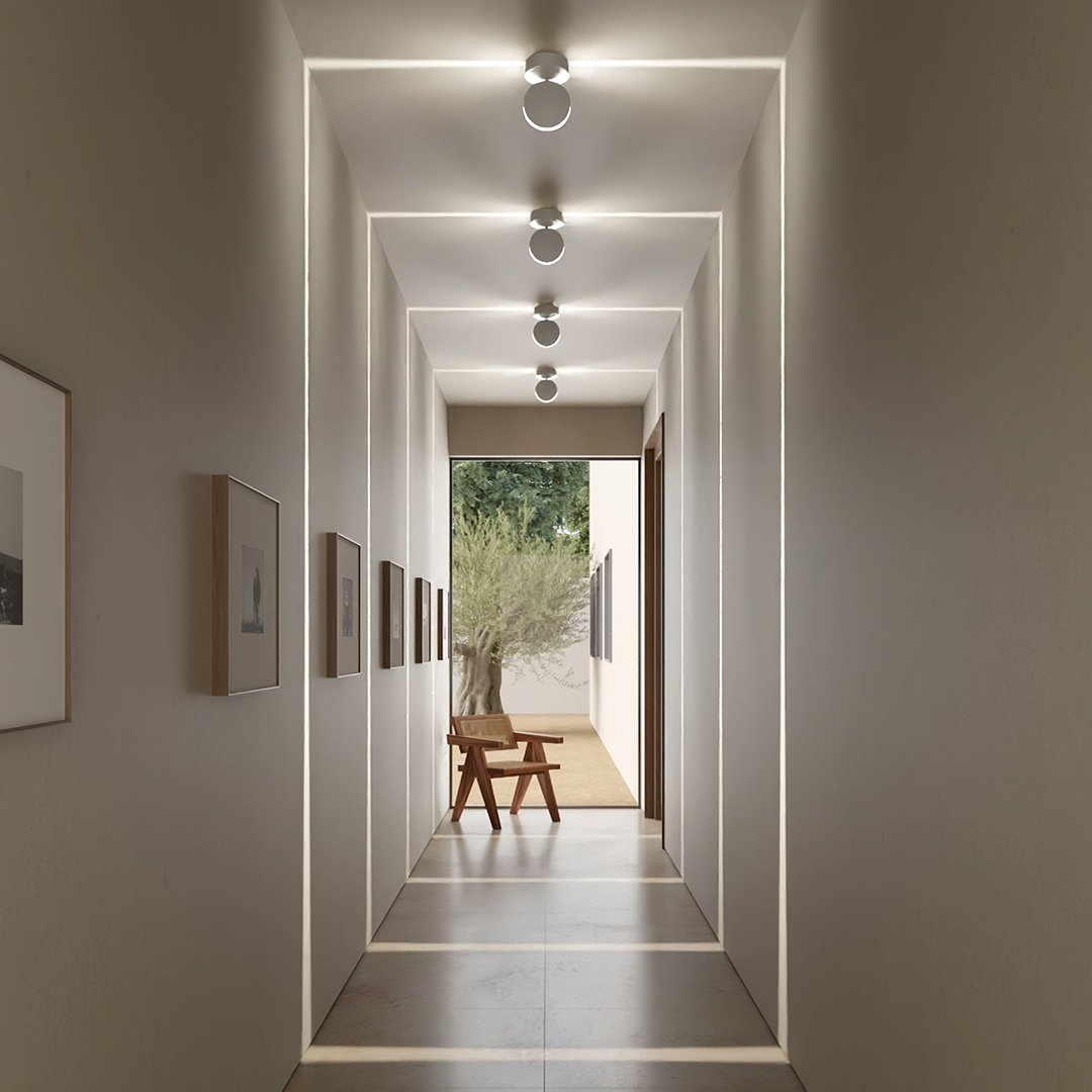 Hallway with four ceiling lights producing glowing square frames of light that repeat along the walls and floor toward a window. 5
