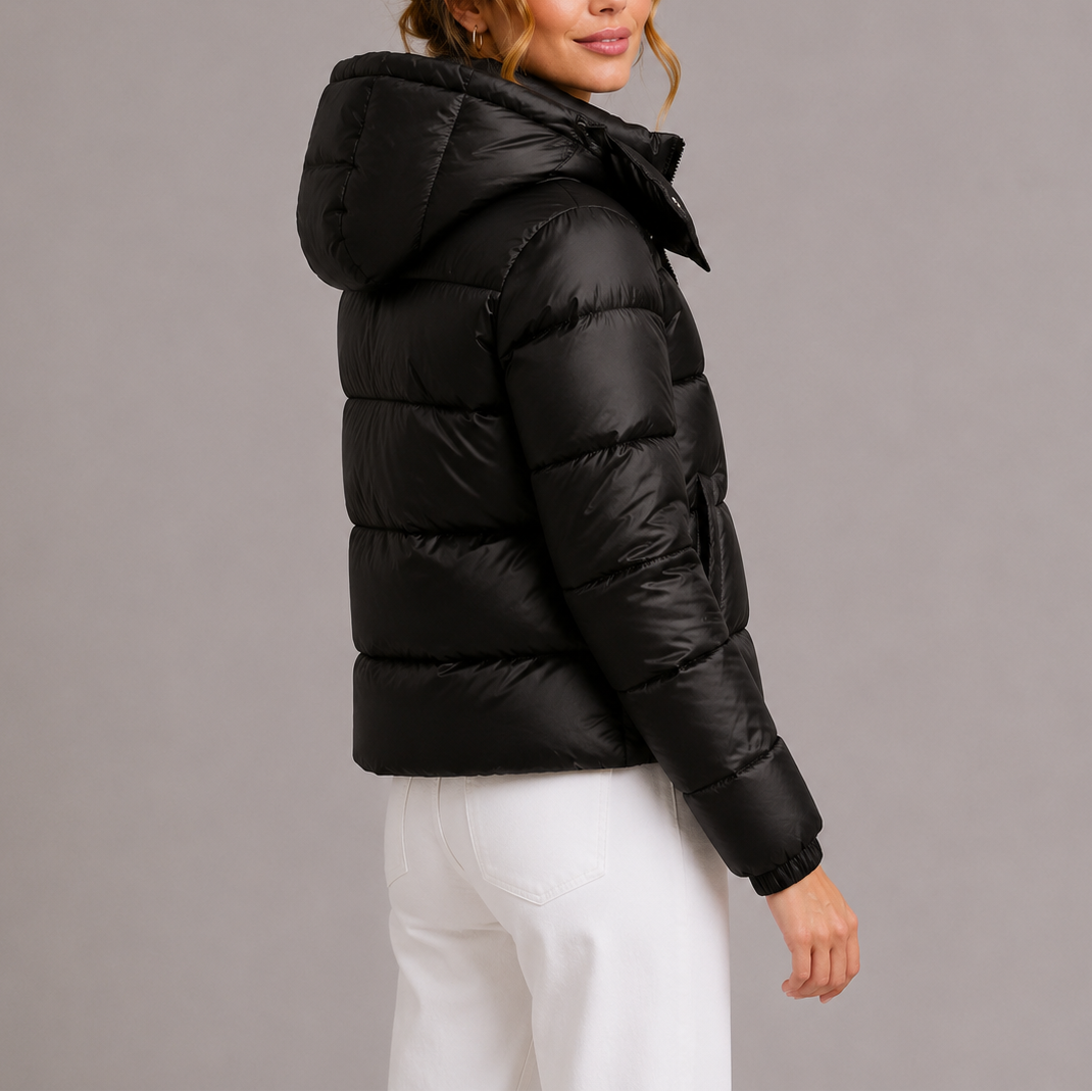 Back three-quarter view of a model wearing the black puffer jacket, showing the hood and horizontal quilting 4