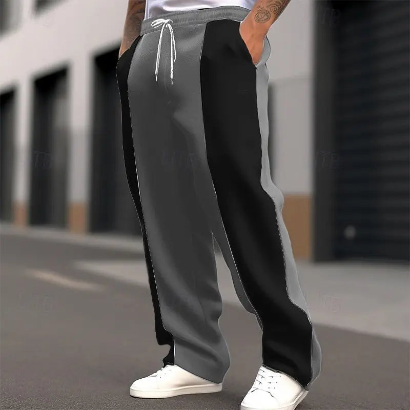 Model wearing grey and black colour-block sweatpants with a white drawstring, hand in pocket, outdoors 5