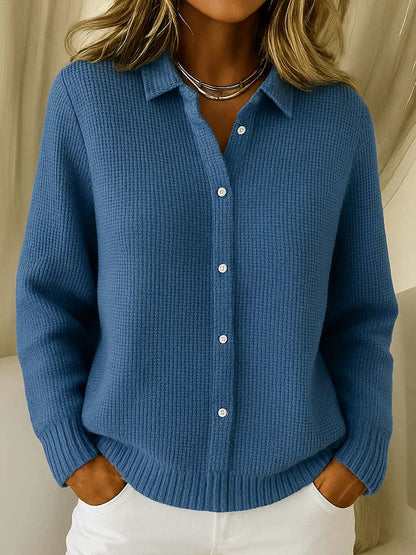Collared button-up knit jumper in a medium denim blue, worn by a model with white trousers and a layered silver necklace. 4