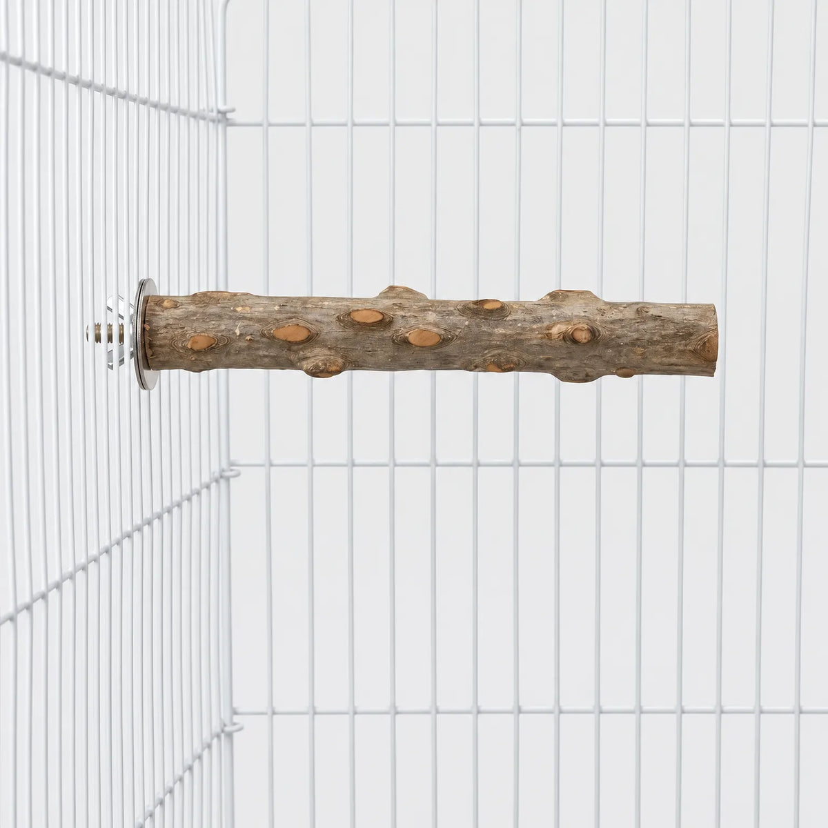 Natural wooden perch with knots and rough bark, bolted horizontally to the white wire side of a cage. 1