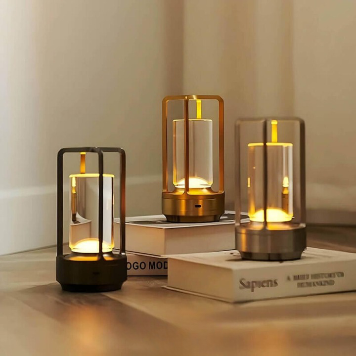 Three lit lamps in black, gold and silver finishes stood on hardback books on a wooden floor in a room corner. 2