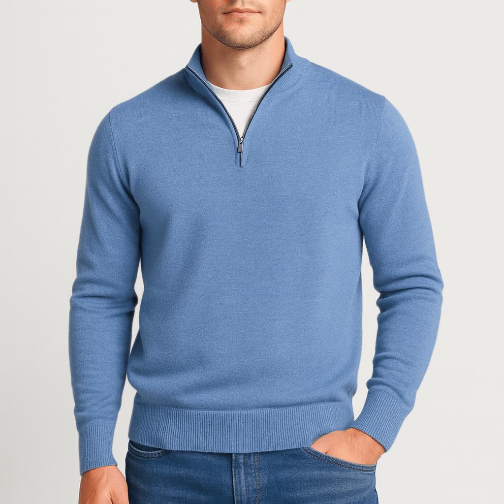Model wearing the quarter-zip jumper in mid blue, one hand in the jeans pocket, white T-shirt visible at the collar. 6