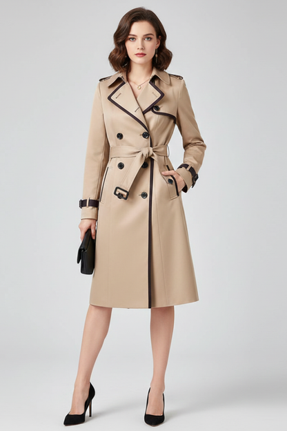 Model facing the camera in the beige trench coat with dark piping, belt tied at the waist, holding a small black clutch. 2