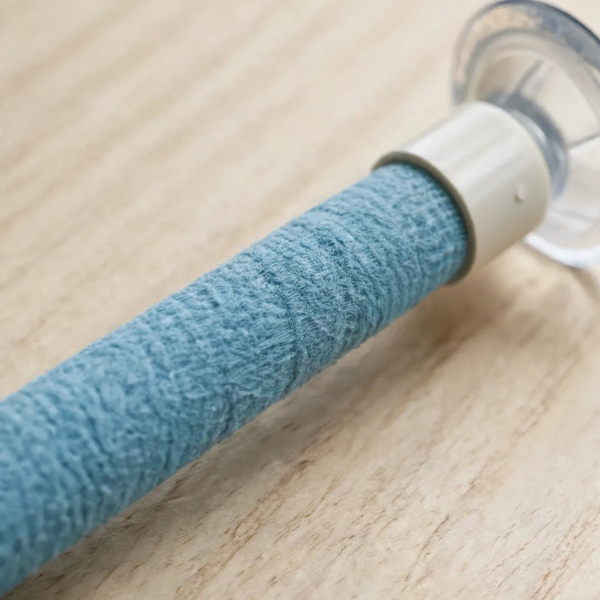 Close-up of the blue textured wrap on the perch, white end cap and clear suction cup, resting on a light wooden surface. 4